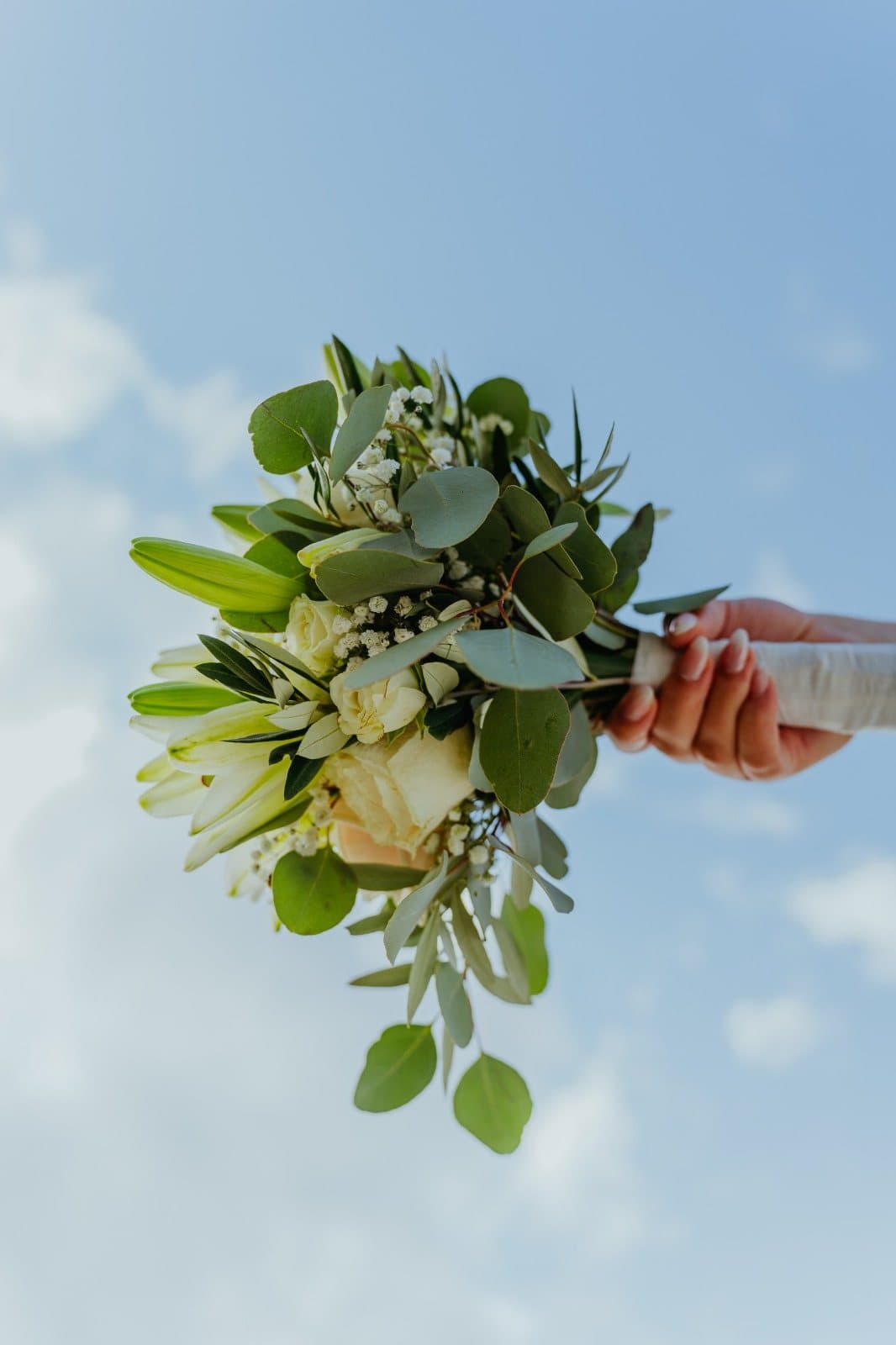 Bouquet de noiva erguido contra o céu azul