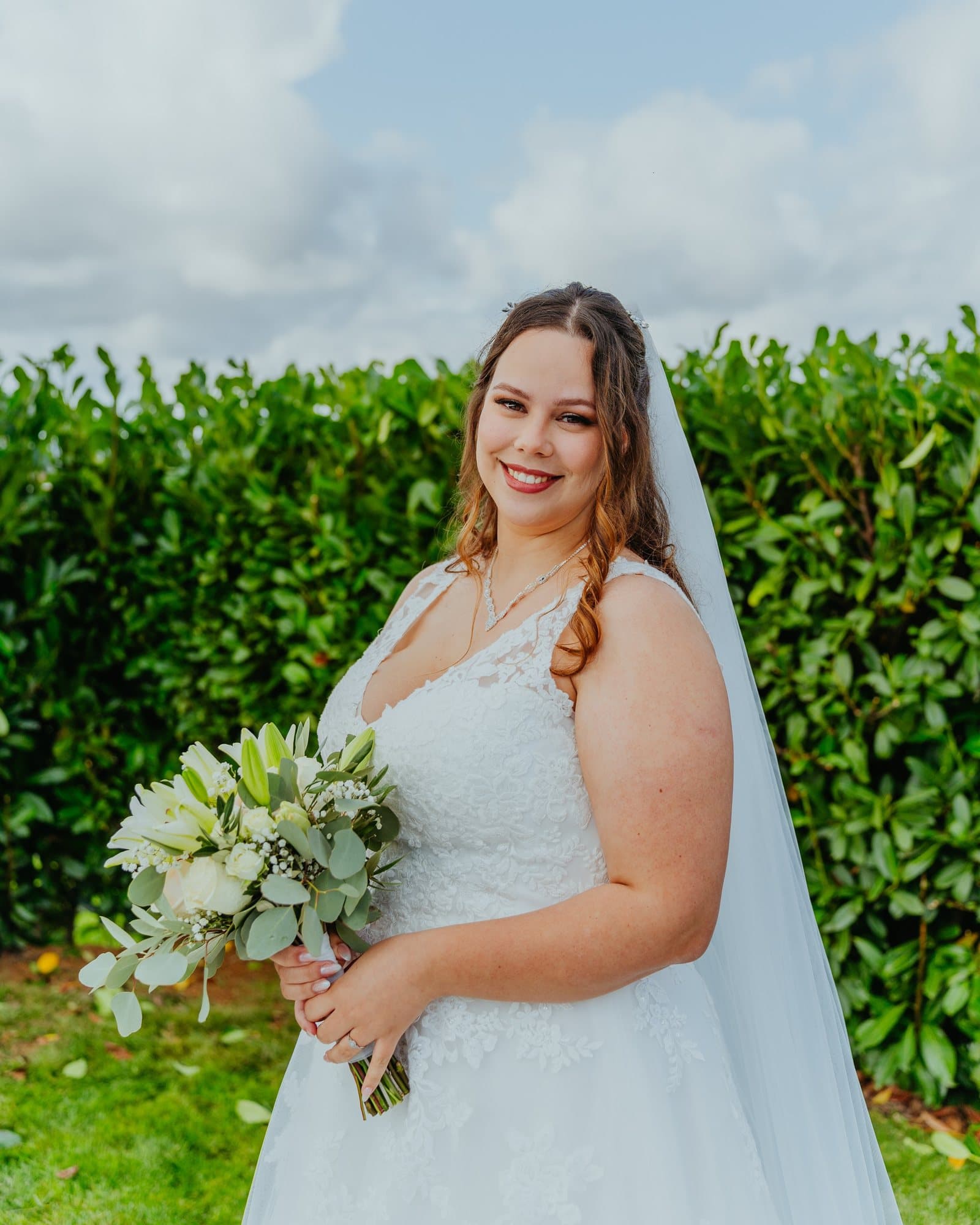 Noiva no jardim, a sorrir, com um bouquet verde e branco