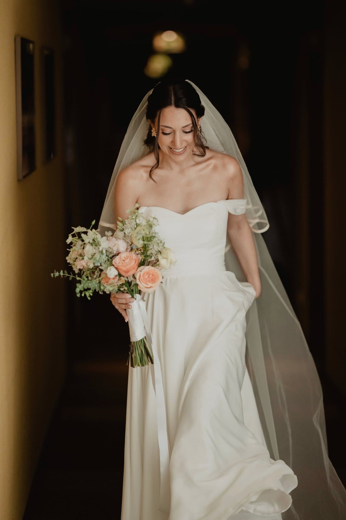 Noiva num corredor escuro, com um bouquet de rosas pêssego
